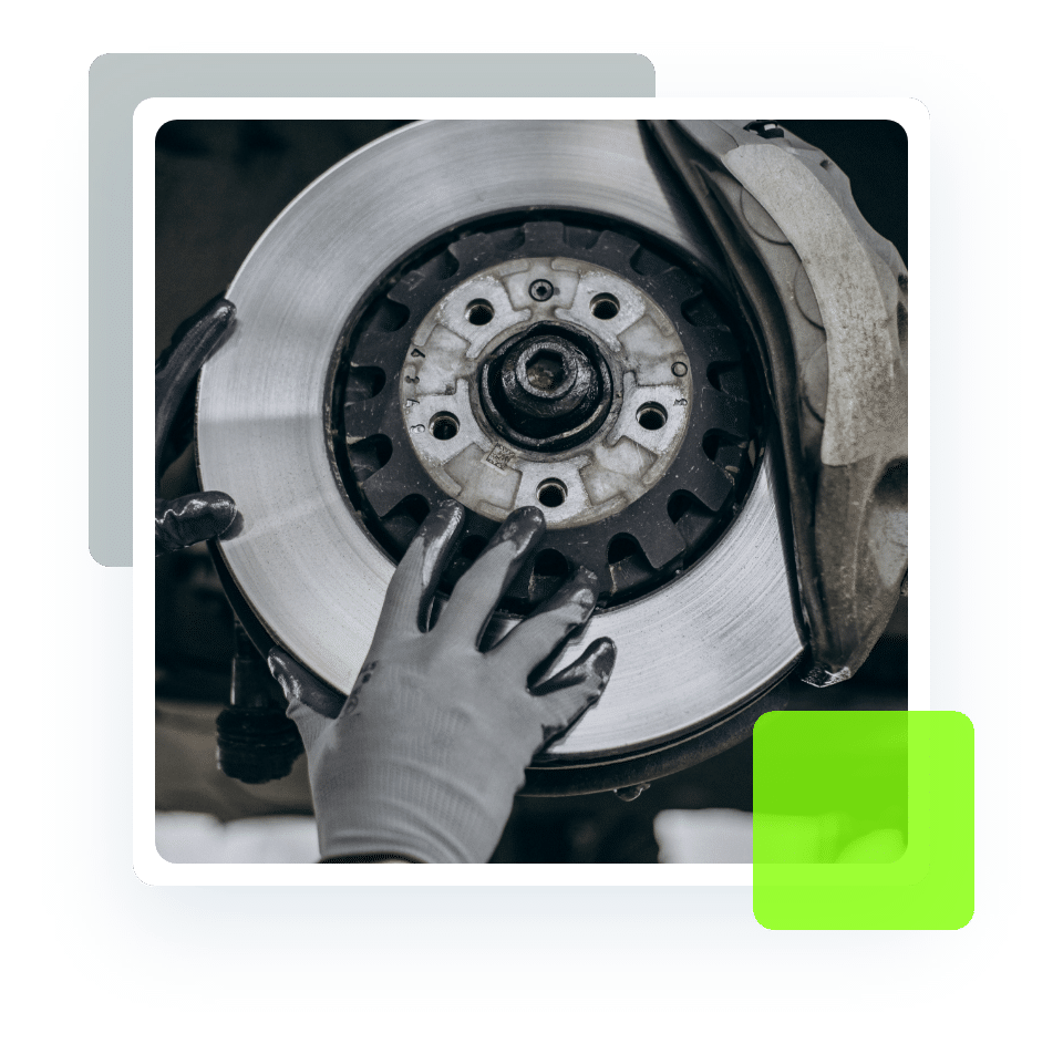 Image of an auto technician's hands in glove holding a brake with exposed rotor and pads. Concept image of brake repair and services at Quality Car Care in North Liberty, IA.