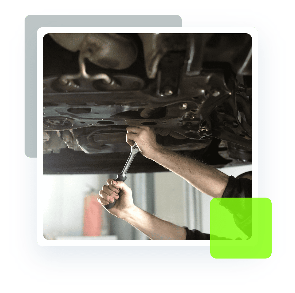 Image of an auto mechanic's hand holding a tool while working under a car on a lift. Concept image of auto repair and maintenance at Quality Car Care in North Liberty, IA.