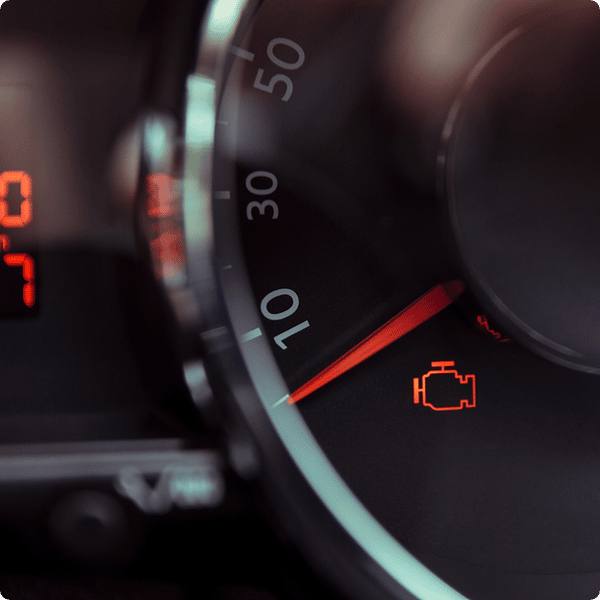 Closeup image of an illuminated check engine on a dashboard.