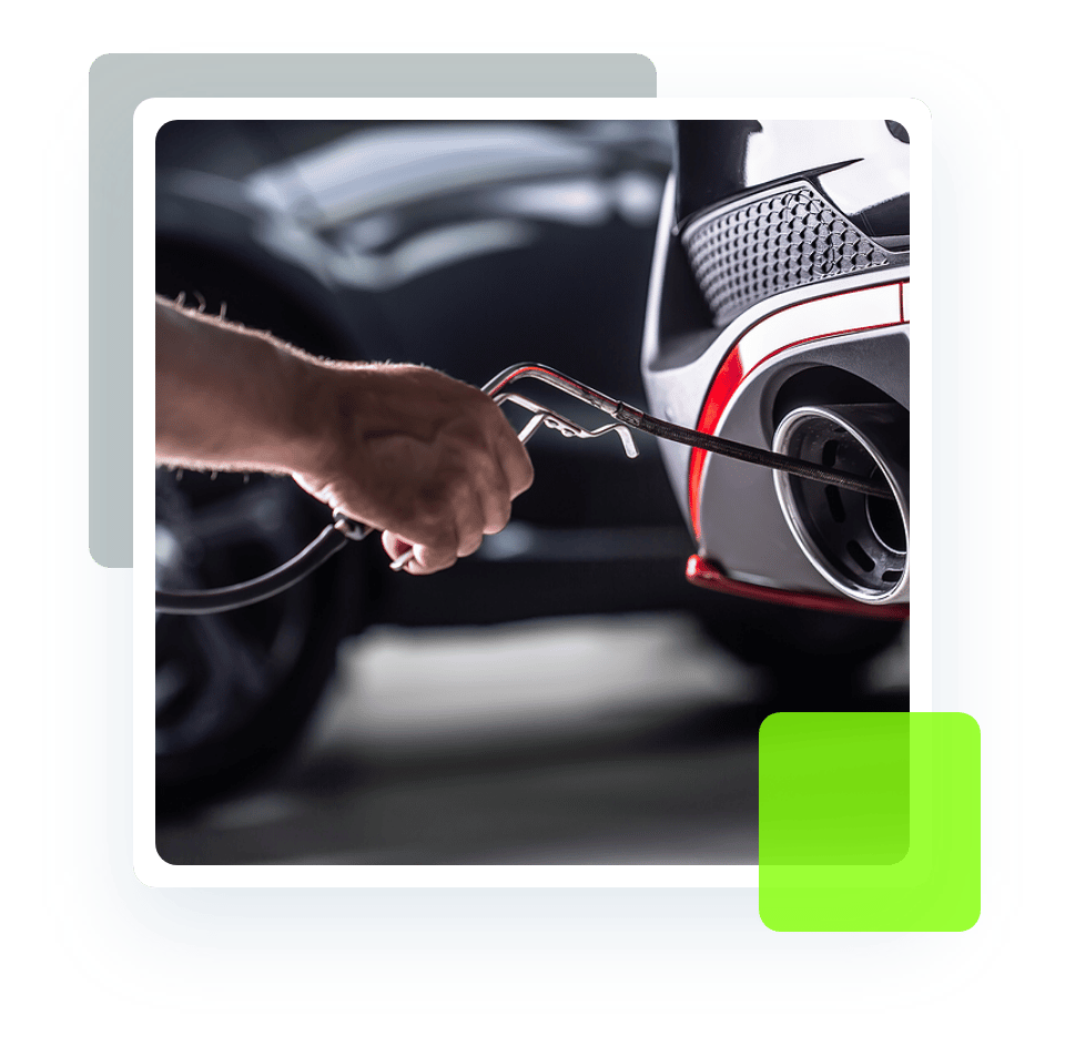 Image of an auto technician holding a car exhaust gas analyzer. Concept image of exhaust repair at Quality Car Care in North Liberty, IA.