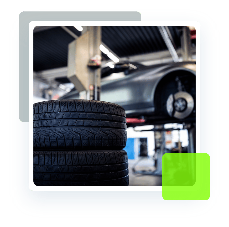 Image of stacked tires and a car on a lift. Concept image of new tires and other tire services at Quality Car Care in North Liberty, IA.