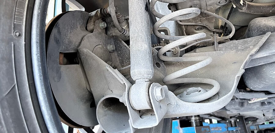 Top 4 Signs You Need Suspension Repair | Quality Car Care in North Liberty, IA. Imag eof an old suspension coil and spring of left rear wheel of an old car.