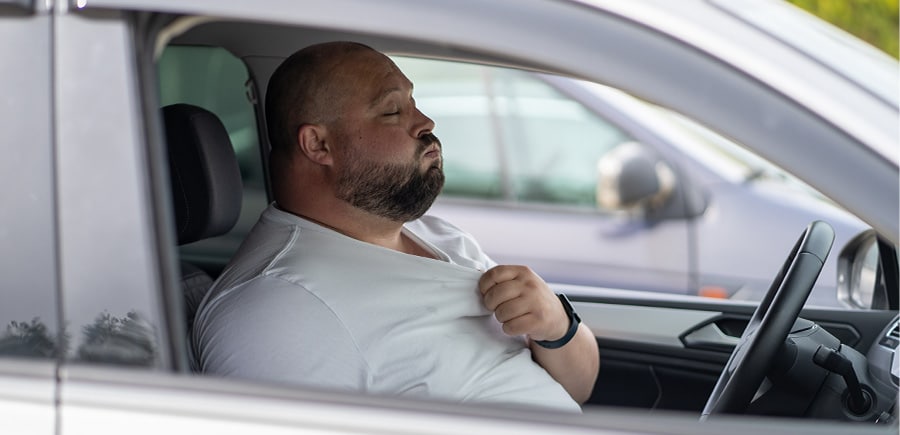 Exhausted man driver sitting inside car under hot weather. Concept image of “Tips on How to Keep Your Car Cool and Comfortable” | Quality Car Care in North Liberty, IA.