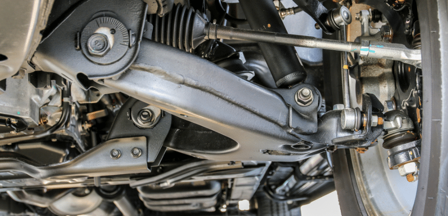 North Liberty's Guide to Car Suspension Repair | Quality Auto Repair. Close up image of car suspension system of a car on a lift in the shop.
