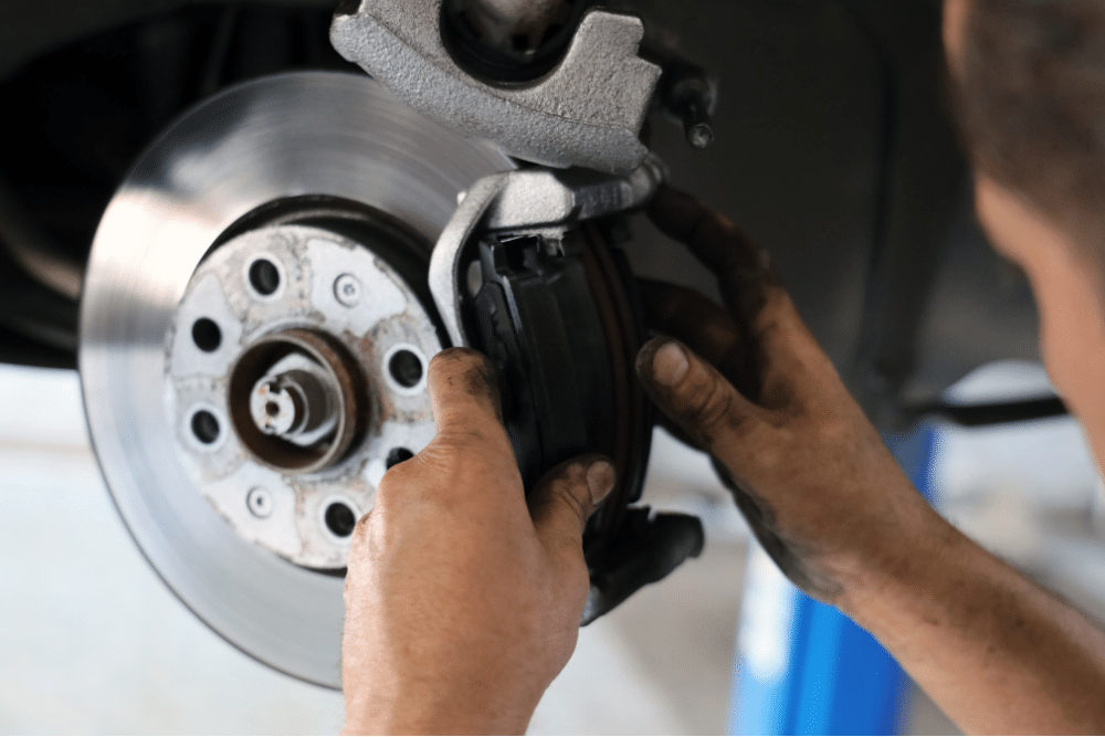 brake services, auto repair in North Liberty, IA by Quality Car Care. A mechanic installs new brake pads on a vehicle’s disc brake system, ensuring optimal stopping power and safety for the road.