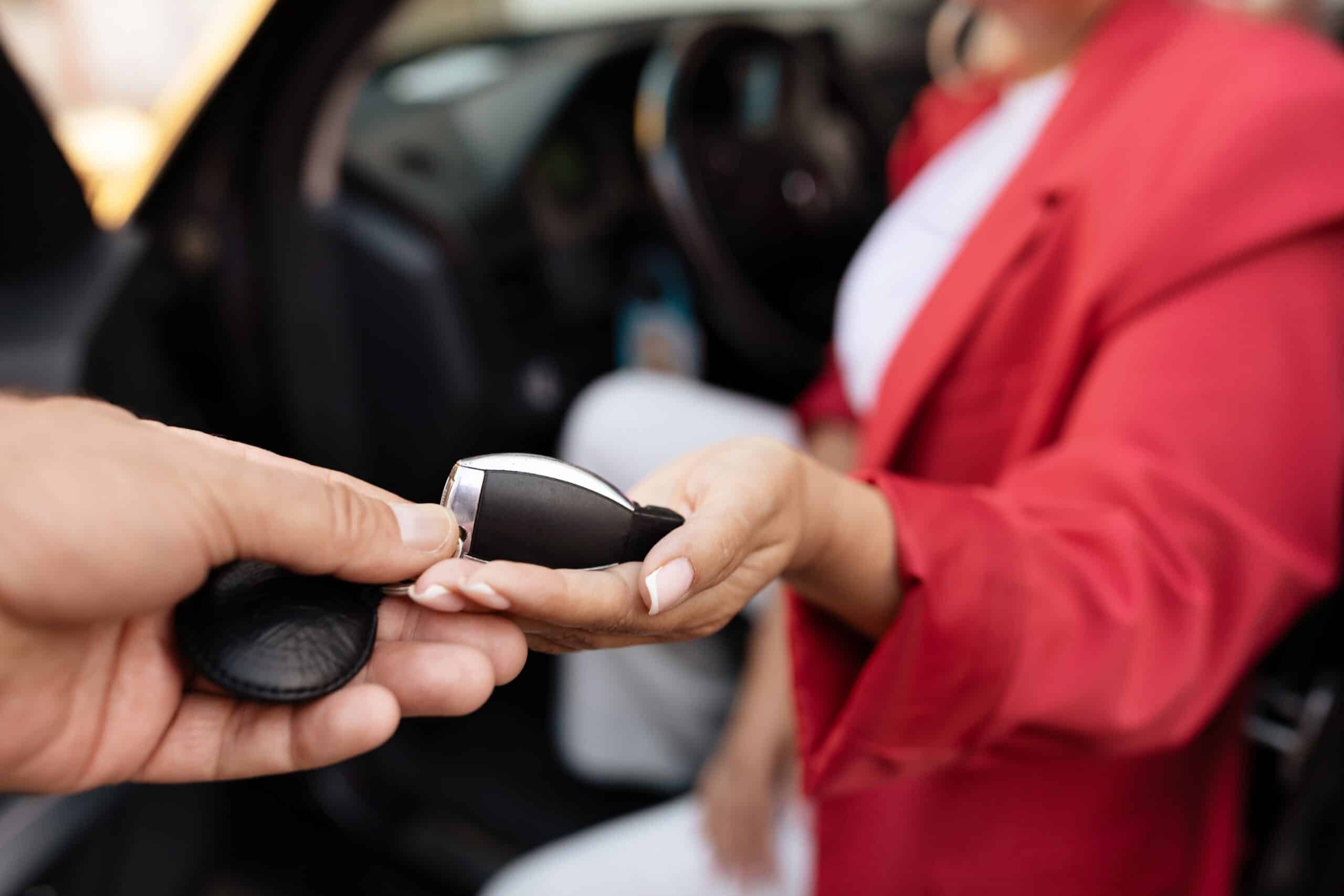 Car Key Fob Reprogramming in North Liberty by Quality Car Care, closeup of a person handing off a car key fob to another person